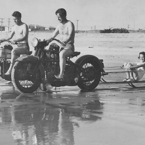 Oceanside Historical Society - 1940-010 Ben Hunsaker and Russ McKenney pulling Marjorie Johnson and Marie Frazee on skis north of the pier circa 1940_resize